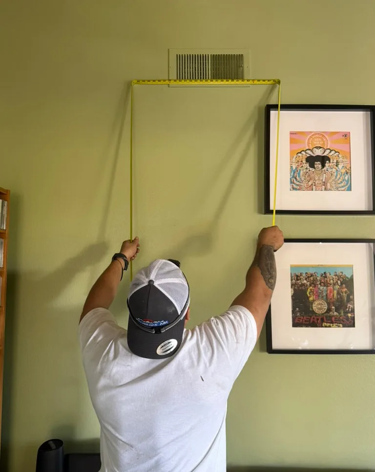 Technician Measuring Wall for AC Vent Placement for Accurate AC Unit Installation